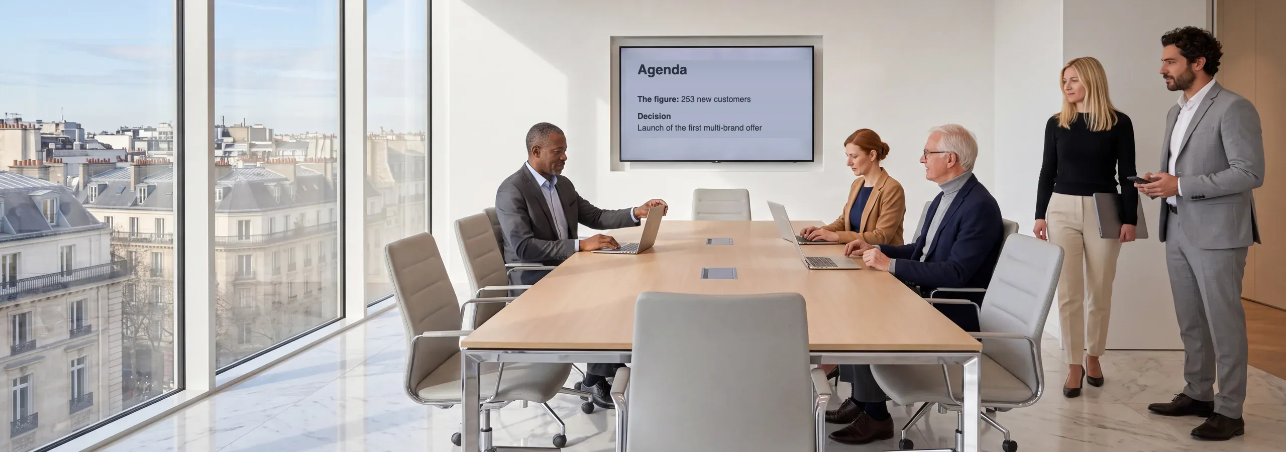 The board room, members taking their seats. On screen, the agenda: the figure, 253 new customers, then the decision, launching the first multi-brand offer.